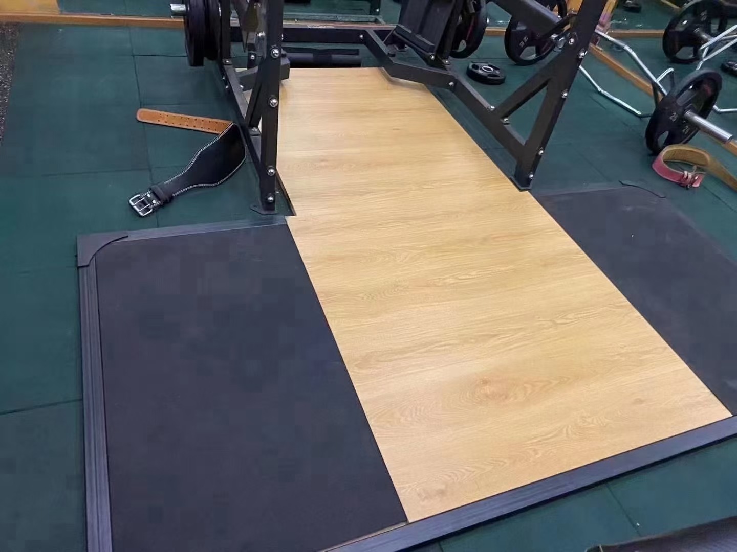 A robust squat training platform with a sturdy frame and a large, flat surface designed for heavy lifting. The platform features a non-slip, textured area for foot placement and an integrated lifting area to protect the floor during intense squats and other powerlifting exercises